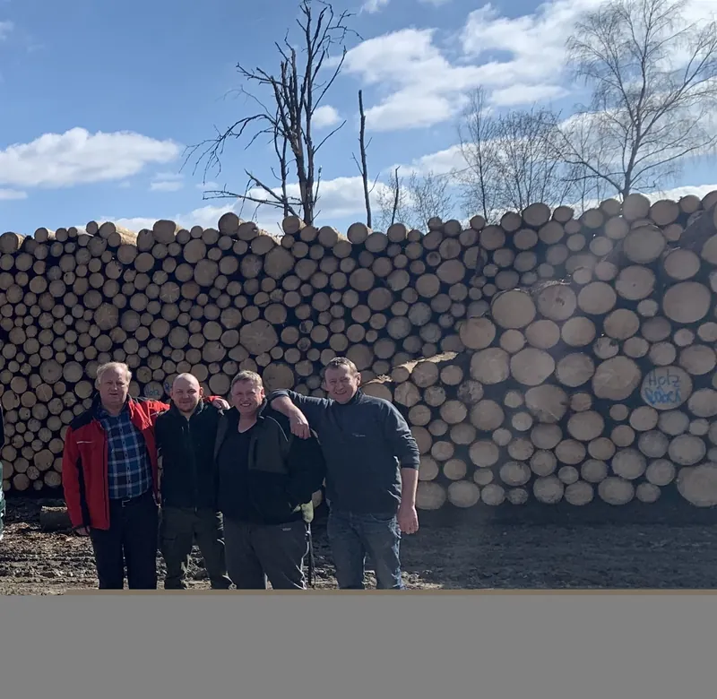 Das eingespielte Team von Holz Reiter vor einem Holzpolter